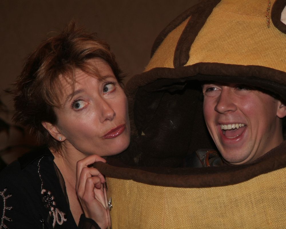 A person poses with a kissing face next to someone in a burlap character costume.